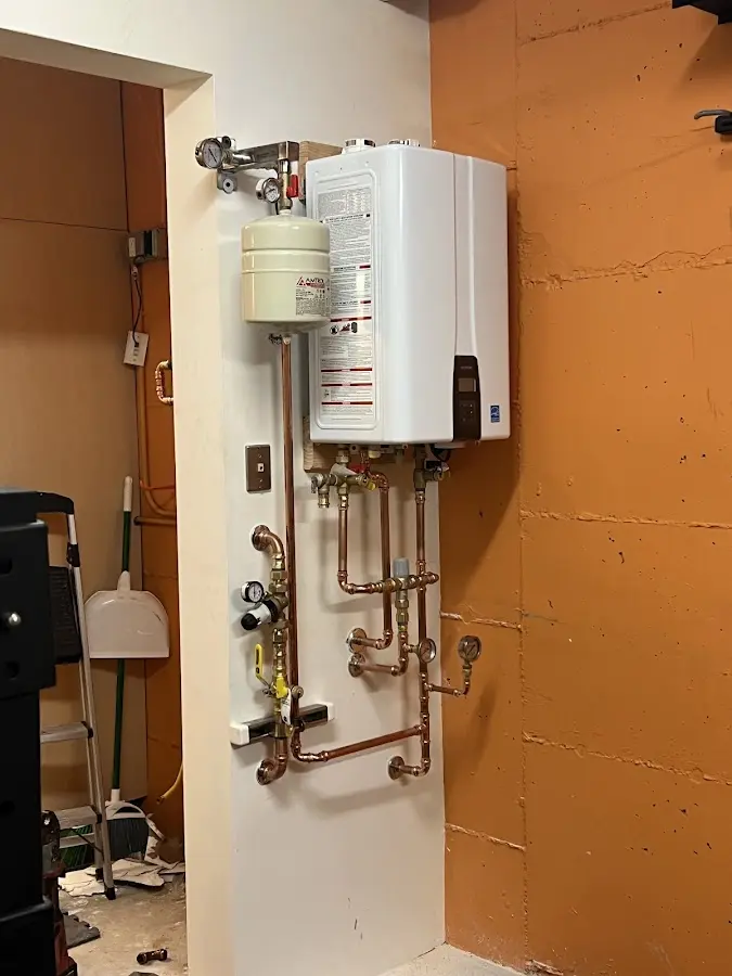 Plumbing technician inspecting water heater connections in Stoughton